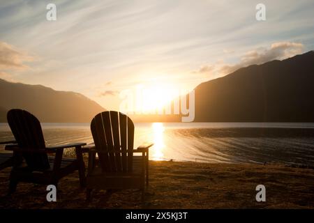 Deux chaises longues en bois de style Adirondack au Crescent Lake Lodge au parc national olympique au coucher du soleil. Banque D'Images