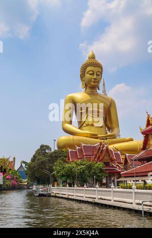 Grande statue de Bouddha haute et dorée au temple Wat Paknam (Pak Nam) Phasi Charoen près d'un canal (khlong) à Bangkok, Thaïlande par une journée ensoleillée. Banque D'Images