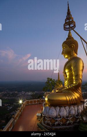 Vue panoramique de la région environnante et une grande statue dorée de Bouddha au temple de la grotte du tigre (Wat Tham Suea (Sua)) à Krabi, Thaïlande au crépuscule. Banque D'Images