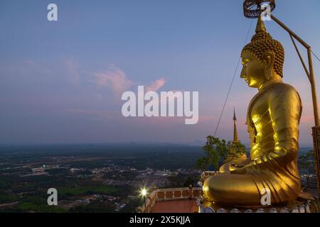 Vue panoramique de la région environnante et une grande statue dorée de Bouddha au temple de la grotte du tigre (Wat Tham Suea (Sua)) à Krabi, Thaïlande au crépuscule. Banque D'Images