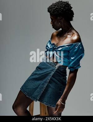 Photo studio d'une jeune femme en top en soie bleue et mini jupe en denim Banque D'Images