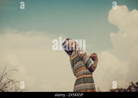 Nigeria, Etat du Delta, femme souriante en robe à motifs contre le ciel Banque D'Images