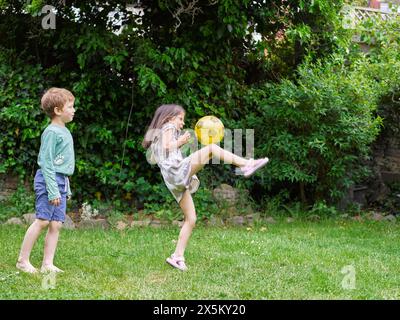 Garçon et fille jouant avec la balle sur la pelouse Banque D'Images