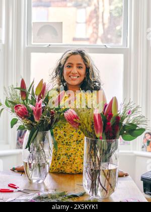 Femme souriante debout à côté de bouquets dans des vases Banque D'Images