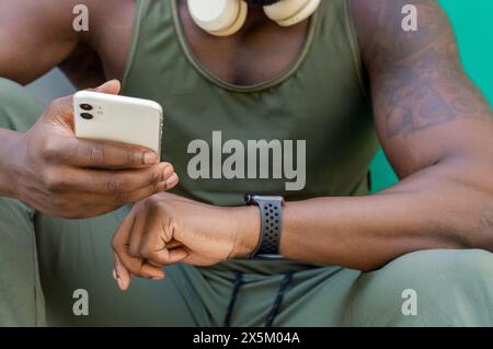 Gros plan de l'homme avec téléphone intelligent, écouteurs et montre-bracelet Banque D'Images