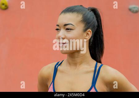 Femme debout contre le mur d'escalade Banque D'Images