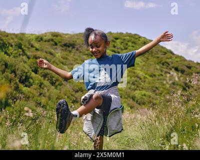 Fille heureuse avec les bras tendus dansant dans les collines Banque D'Images