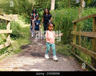 Famille avec enfants marchant à travers la passerelle dans la forêt Banque D'Images