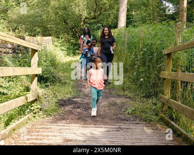 Famille avec enfants marchant à travers la passerelle dans la forêt Banque D'Images