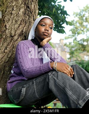 Royaume-Uni, Londres, jeune femme portant le hijab assis près du tronc d'arbre Banque D'Images