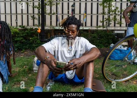 USA, jeune homme élégant assis sur l'herbe dans le parc avec téléphone intelligent Banque D'Images