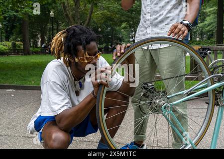 USA, homme réparant roue de vélo dans le parc Banque D'Images