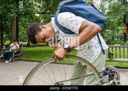 USA, homme réparant roue de vélo dans le parc Banque D'Images