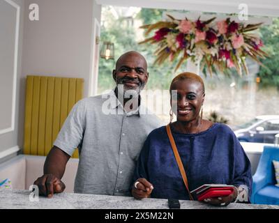 Royaume-Uni, Portrait d'un couple d'adultes détenant des passeports à la réception de l'hôtel Banque D'Images