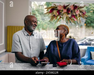 Royaume-Uni, couple d'adultes souriant tenant des passeports à la réception de l'hôtel Banque D'Images