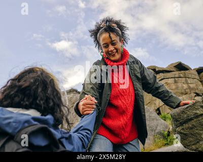 Femme aidant son collègue randonneur à escalader une montagne rocheuse Banque D'Images