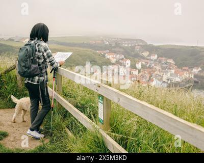 Royaume-Uni, randonneur féminin avec chien regardant la carte dans le paysage Banque D'Images