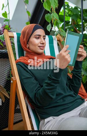 Femme portant le foulard livre de lecture à la maison Banque D'Images