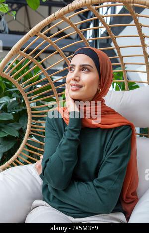 Portrait d'une femme portant un foulard assis dans une chaise pivotante Banque D'Images