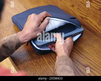 Gros plan des mains d'hommes mettant l'ordinateur portable dans le sac Banque D'Images