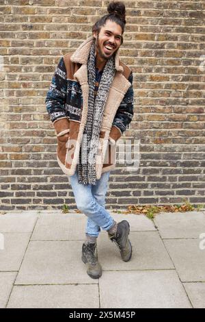 Portrait of mid adult man in front of brick wall Banque D'Images