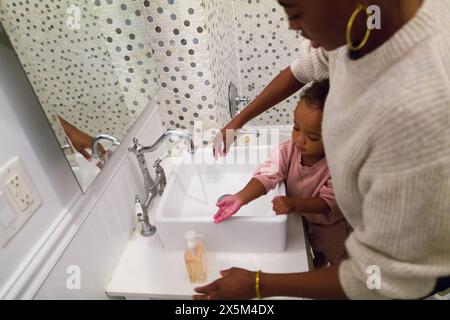 La mère et la fille se lavent les mains dans la salle de bains Banque D'Images