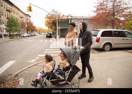 Parents marchant dans la rue avec des filles en poussette Banque D'Images