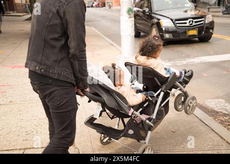 Père traversant la rue avec des filles en poussette Banque D'Images