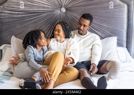 Garçon avec mère et père avec jambe prothétique sur le lit Banque D'Images