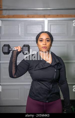 Femme exerçant avec des haltères dans le gymnase Banque D'Images