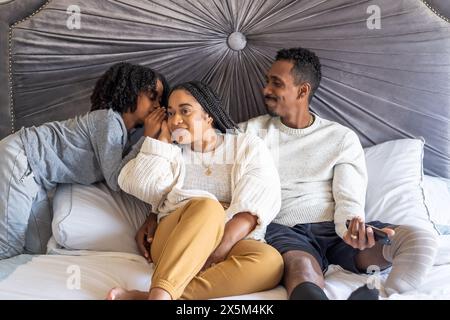 Garçon avec mère et père avec jambe prothétique sur le lit Banque D'Images