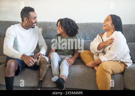 Garçon avec mère et père avec jambe prothétique assis sur le canapé Banque D'Images