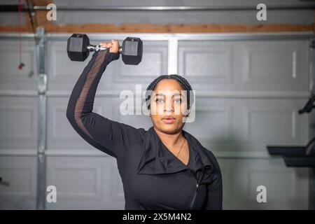 Femme exerçant avec des haltères dans le gymnase Banque D'Images