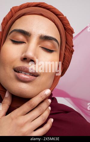 Portrait de studio d'une femme portant du brownhijab avec les yeux fermés Banque D'Images