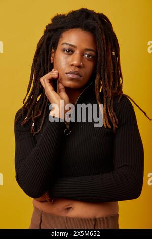 Portrait studio de femme avec des dreadlocks sur fond jaune Banque D'Images