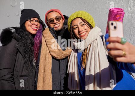 USA, New York City, amis souriants dans des vêtements chauds prenant selfie à l'extérieur Banque D'Images