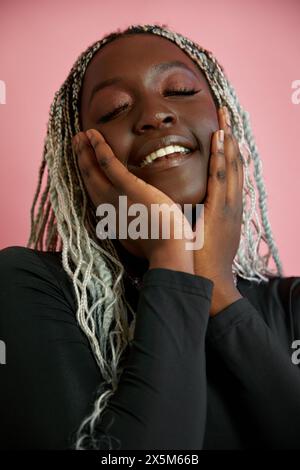 Portrait d'une femme souriante avec des cheveux tressés blanchis et les yeux fermés Banque D'Images