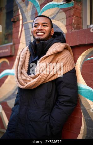 USA, New York City, Portrait d'homme queer souriant en veste et foulard Banque D'Images