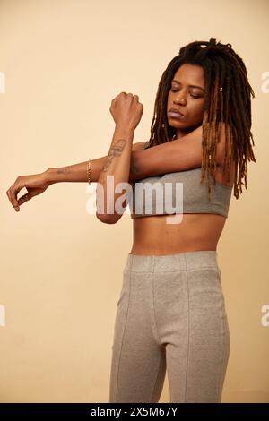 Photo de studio d'une femme avec des dreadlocks étirant le bras Banque D'Images