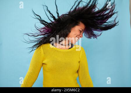 Photo de studio d'une femme souriante secouant la tête sur fond bleu Banque D'Images