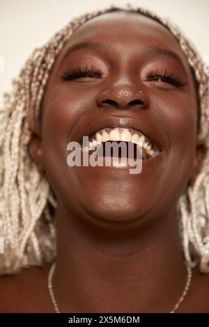 Gros plan d'une femme souriante avec des cheveux tressés blanchis Banque D'Images