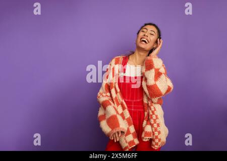 Portrait de studio de femme souriante sur fond violet Banque D'Images