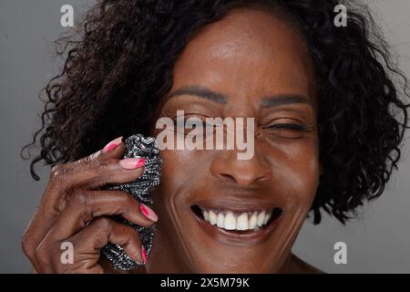 Portrait de studio de femme mature tenant un tampon à récurer Banque D'Images