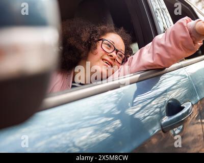 Girl leaning out of car window Banque D'Images