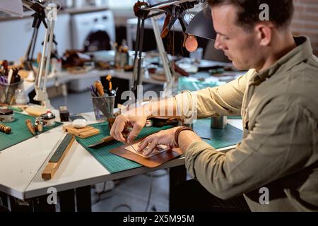 jeune artisan talentueux perce ou agrandit les trous existants dans divers matériaux, gros plan portrait de côté Banque D'Images