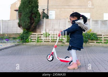 Girl riding scooter push Banque D'Images