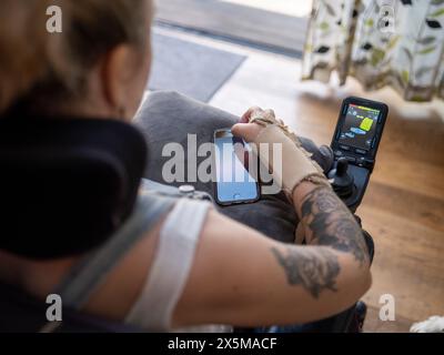 Femme en fauteuil roulant électrique en utilisant le téléphone Banque D'Images