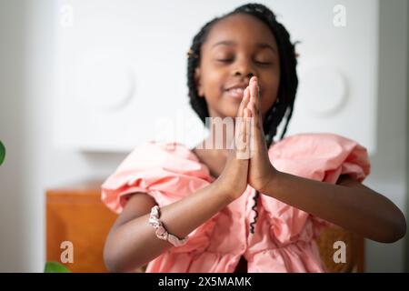 Fille souriante (6-7) priant Banque D'Images