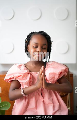 Fille souriante (6-7) priant Banque D'Images