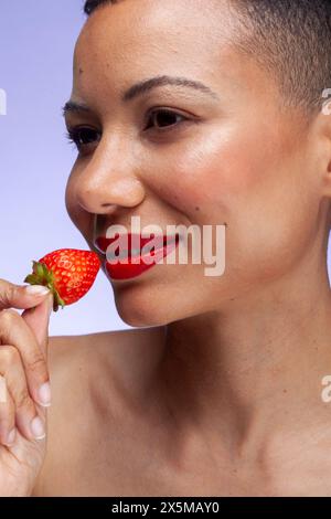 Gros plan d'une femme souriante tenant une fraise Banque D'Images